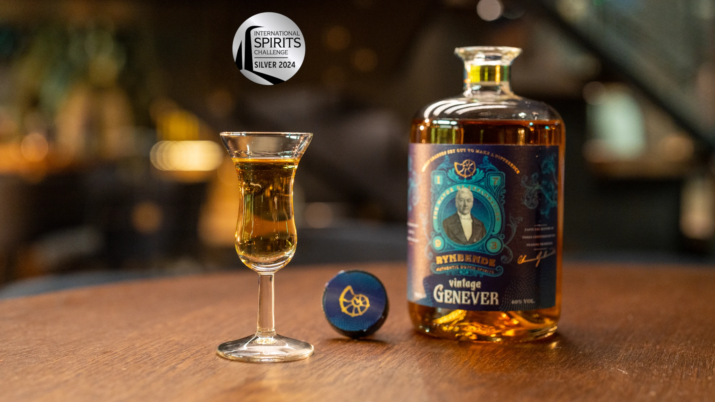 Rynbende's Vintage Genever met een gevulde tulpglas ernaast op een houten tafel. En de Zilveren ISC award is zichtbaar